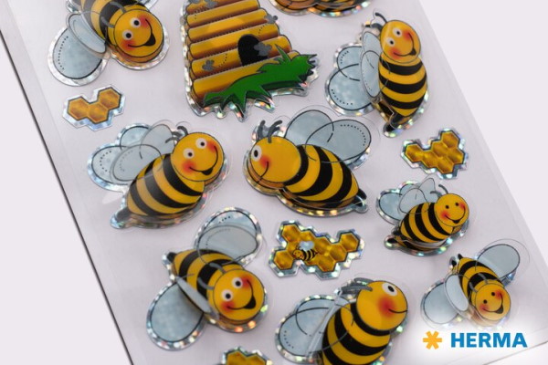 Bunte HERMA Aufkleber von Bienen, einem Bienenstock und Honigwaben, mit lächelnden Gesichtern und glänzenden Oberflächen.