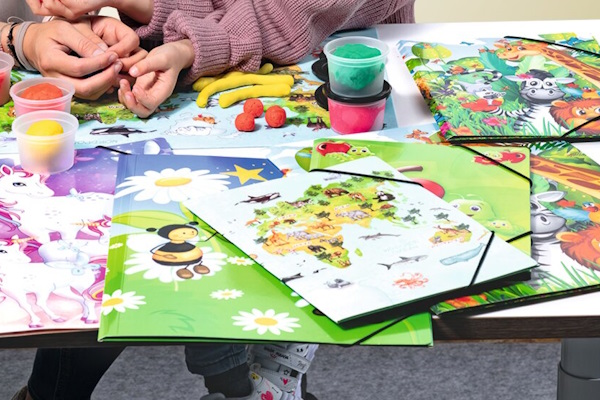 Schreibtisch mit verschiedenen bunten Sammelmappen mit Kindermotiven
