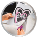 Eine Person schneidet ein Herz aus Papier mit der Aufschrift "Bride" mit einer Schere.