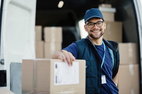 Paketbote mit Päckchen auf dem ein Versandetikett klebt