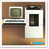 Ein Computer mit Monitor und Tastatur steht neben einem weißen Gerät, das wie ein Drucker oder Scanner aussieht.