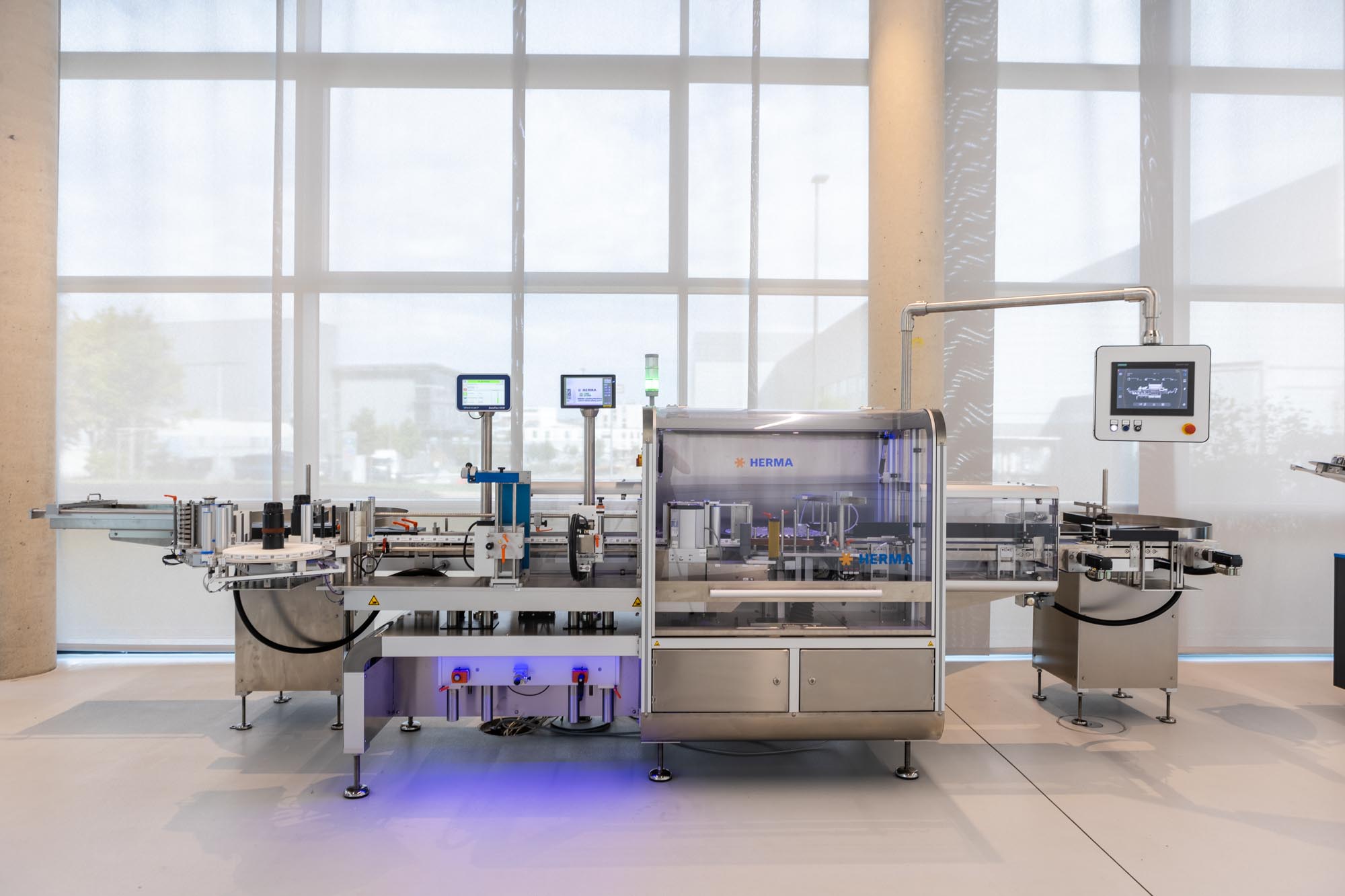 Automatische Abfüll- und Etikettieranlage in einer modernen Produktionsumgebung mit mehreren Bildschirmen zur Überwachung.