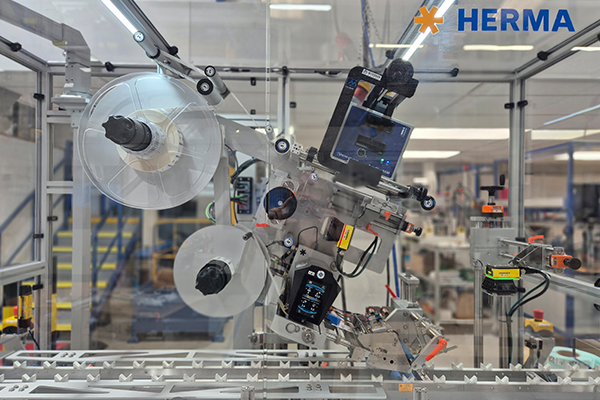 Automatisierte Etikettiermaschine mit Rollen und Steuerungseinheit in einer Produktionsumgebung.