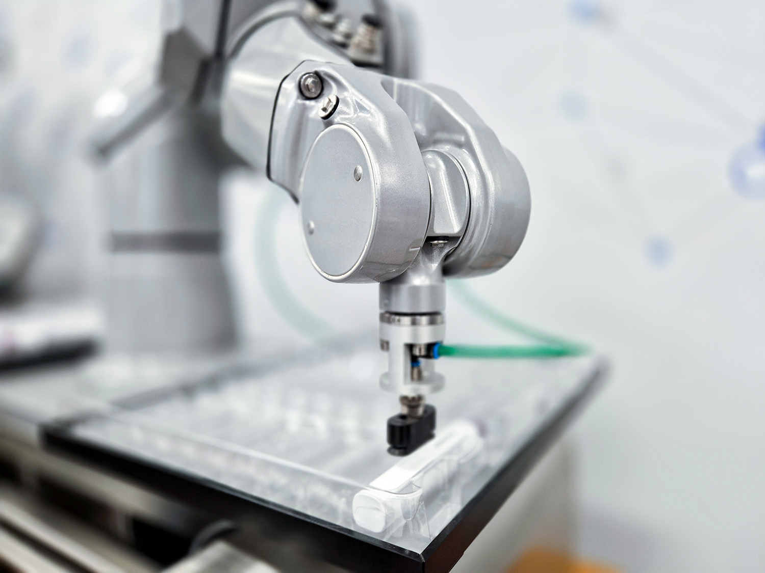 Industrieroboterarm mit Greifer, der auf einer transparenten Oberfläche positioniert ist, bereit zum Greifen eines Objekts.