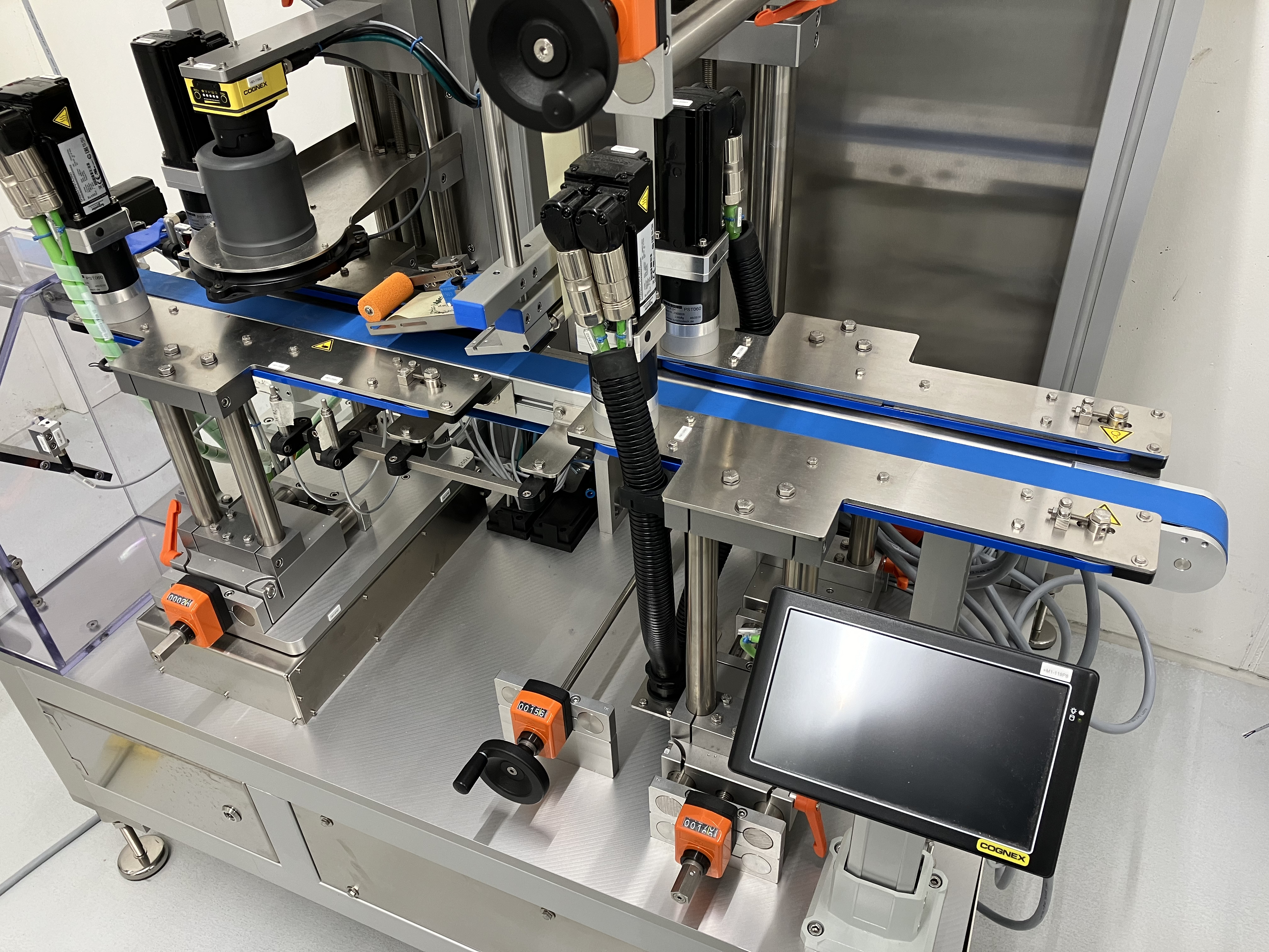 Automatisierte Maschinenanlage mit Förderband, Sensoren und Steuerungseinheit zur Verarbeitung oder Etikettierung von Produkten.