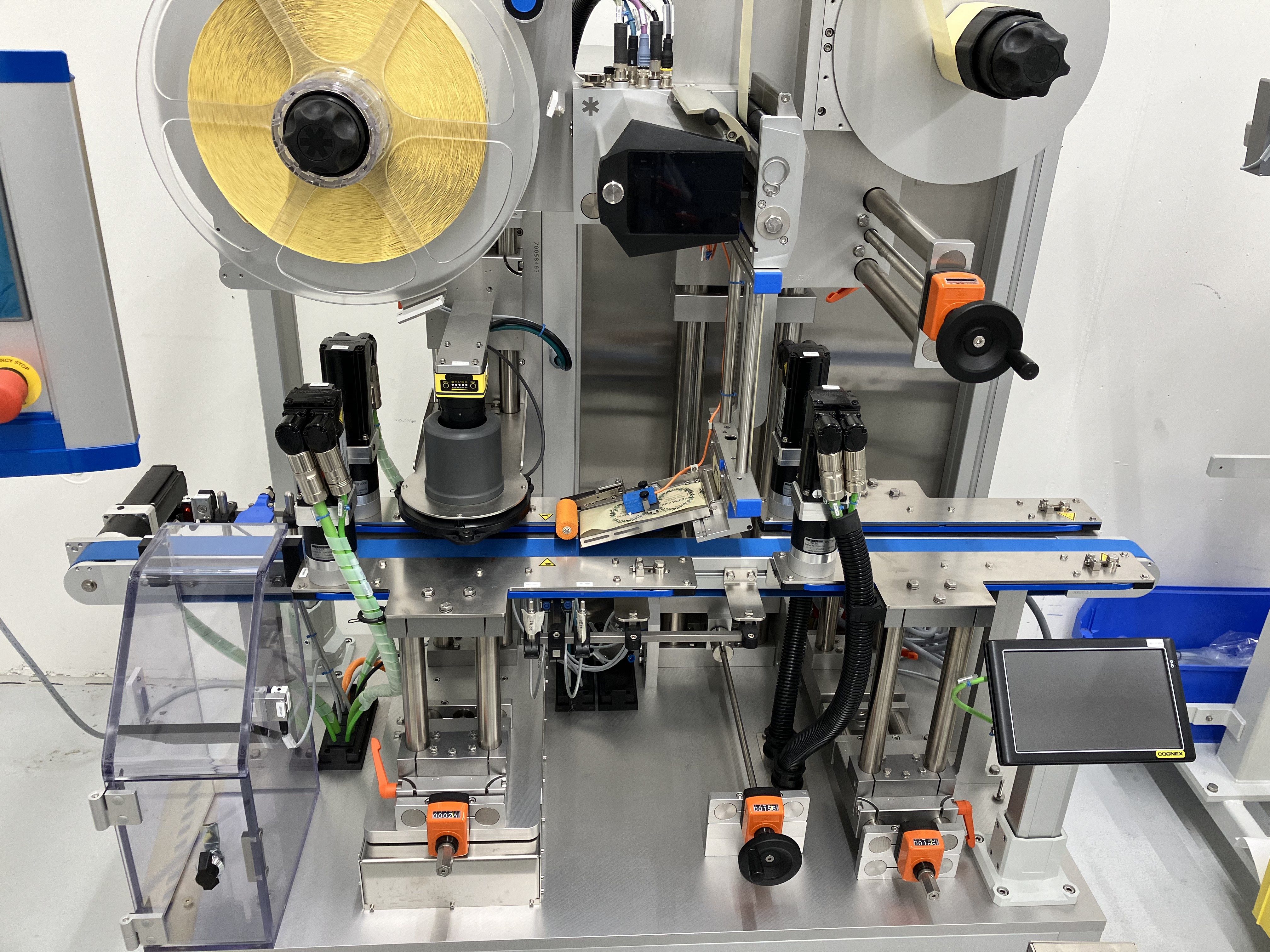 Automatisierte Maschine mit Rollen, Sensoren und Steuerungseinheit zur Verarbeitung und Etikettierung von Materialien.