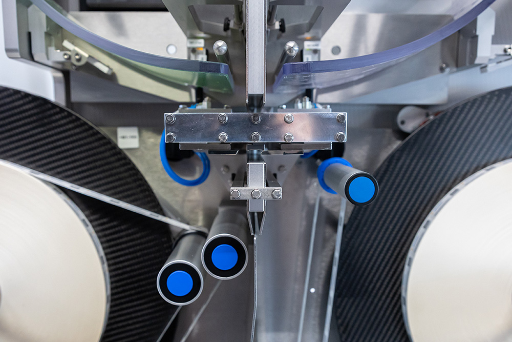 Maschine mit mehreren Rohren und blauen Griffen, die für die Verarbeitung von Materialien oder Produkten konzipiert ist.