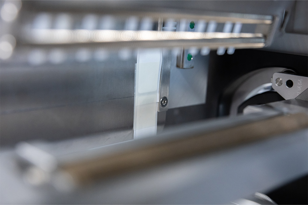 Ein Blick auf die Innenteile einer Maschine mit metallischen Komponenten und einem weißen Element, das in einem mechanischen System positioniert ist.