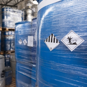 Gefahrstoff- und Gefahrgut-Etiketten: Gefahrgutetiketten auf in Folie eingeschrumpften Behältern in der Chemiebranche