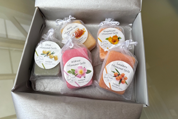 Etsy Seifenetiketten: in einem grauen Karten liegen 5 in Seidenbeutel verpackte Naturseiten. Die Seifenetiketten sind gestaltet mit dem Etsy-Verkäufer-Logo und Inhaltsbeschreibung.