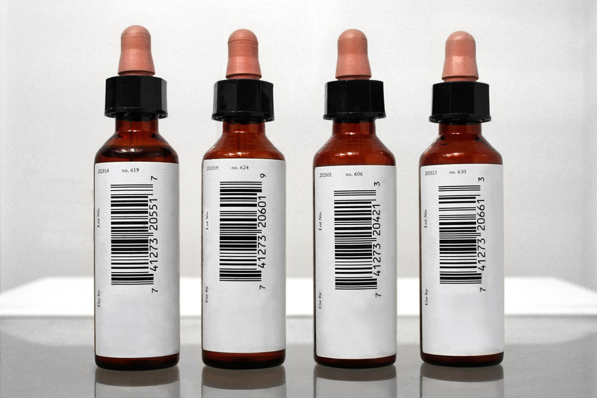 Rundbeklebung: Barcode Etiketten auf vier braunen Arzneifläschchen mit Pipettenverschluss