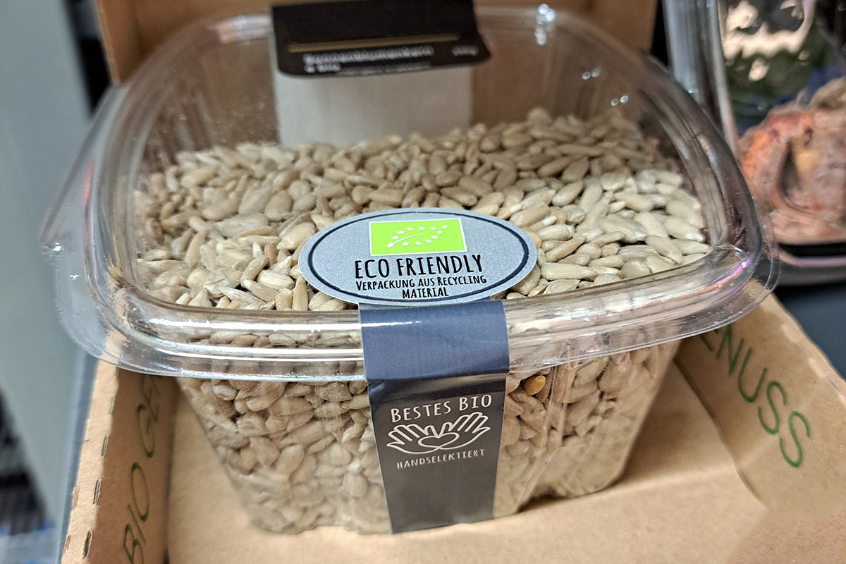 Lösungen Lebensmittel: Two-in-one Produkt- und Verschlussetikett, farbig bedruckt, verbindet Deckel und Korpus einer Clamshell-Packung mit Nüssen