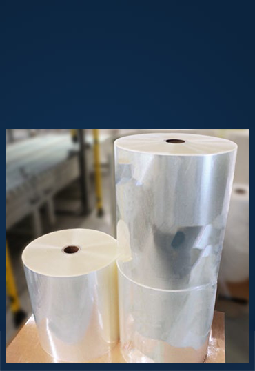 Zwei Rollen transparenter Folie, eine große und eine kleinere, stehen auf einem Tisch in einer Produktionsumgebung.