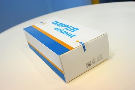 Verpackung mit der Aufschrift "TAMPER evident" in blauer Schrift auf weißem Hintergrund, mit einem orangefarbenen Streifen.