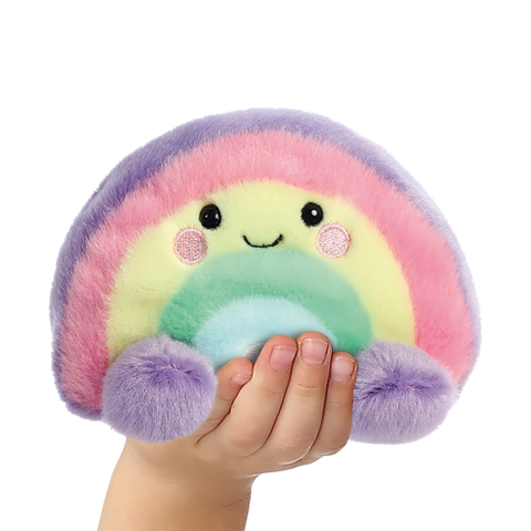 Ein Hand hält ein buntes, kuscheliges Regenbogen-Plüschtier mit einem lächelnden Gesicht und runden, farbigen Details.