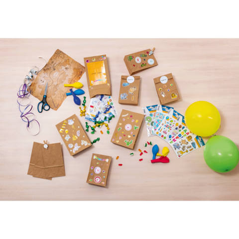 Bastelmaterialien auf einem Tisch, darunter Papiertüten, Aufkleber, Scheren, Luftballons und bunte Perlen.