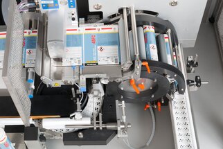 Eine industrielle Etikettiermaschine mit verschiedenen Rollen und einem Förderband, die für das Etikettieren von Produkten verwendet wird.