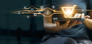 Eine Person hält ein Tablet, während digitale Symbole für Online-Shopping und Dienstleistungen um einen Einkaufswagen schweben.
