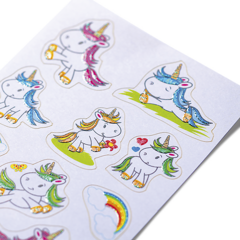 Bunte Einhorn-Aufkleber auf einem weißen Hintergrund, einige mit Blumen und Regenbogenmotiven, glänzend und kindgerecht gestaltet.