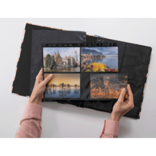 Eine Person hält ein Fotoalbum mit vier Bildern, darunter Landschaften und Stadtansichten, während der Hintergrund schwarz ist.