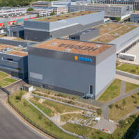 Moderne Industriegebäude mit begrünten Dächern und dem Logo von Merima, umgeben von Straßen und Grünflächen.