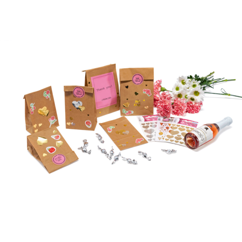 Geschenktüten mit Aufklebern, eine Flasche Sekt und Blumenarrangement. Verschiedene Karten mit "Danke"-Botschaften und Dekorationen.
