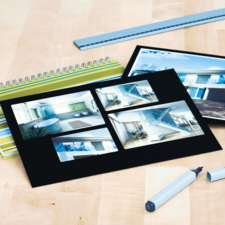 Ein Skizzenbuch mit mehreren Bildern von modernen Innenräumen, darunter Badezimmer und Wohnräume, liegt auf einem Tisch.