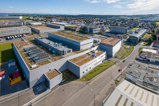 Luftaufnahme eines Industriegebiets mit mehreren modernen Gebäuden, begrünten Dächern und angrenzenden Straßen.
