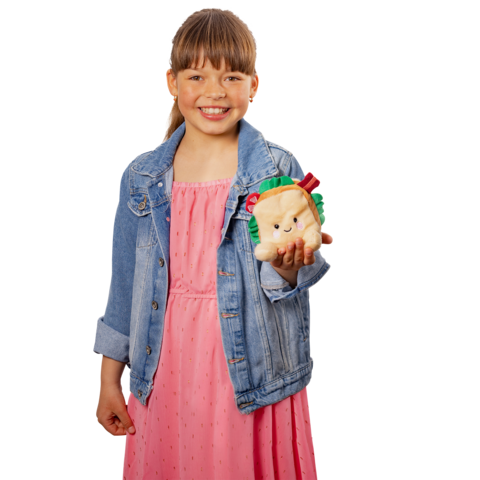 Ein Mädchen in einem rosa Kleid und einer Jeansjacke hält ein plüschiges Spielzeug in Form eines Tieres mit einem Hamburger.