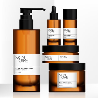 Fünf Hautpflegeprodukte in braunen Flaschen, darunter Handseife, Öl und Cremes, mit weißen Etiketten und der Aufschrift "Pink Grapefruit".