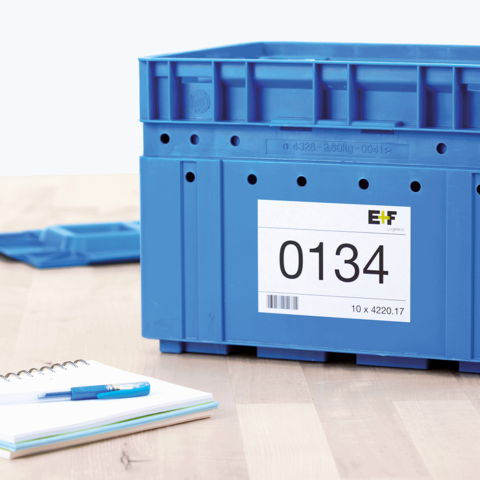 Blaue Kunststoffbox mit einer Etikette, die die Nummer 0134 zeigt. Neben der Box liegen ein Notizblock und ein Stift.