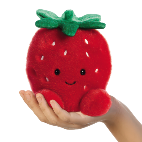 Eine Hand hält ein rotes, kuscheliges Erdbeer-Plüschtier mit einem lächelnden Gesicht und grünen Blättern oben.