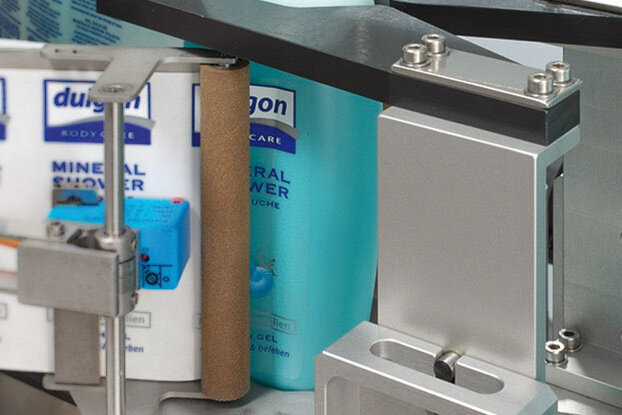 Flasche mit "Dulgon Mineral Shower" steht in einer Produktionslinie, umgeben von weiteren Flaschen des gleichen Produkts.