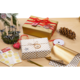 Geschenkverpackungen in Gold und Weiß mit Punkten, umgeben von Dekorationen wie Kerzen, Tannenzapfen und Geschenkband auf einem Tisch.