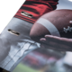 Ein Football wird von einer Hand gehalten, während ein Teil eines roten Trikots und einer grauen Hose sichtbar ist.