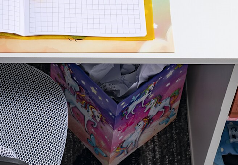 Bunter Papierkorb mit Einhorn Motiv unter einem Schreibtisch