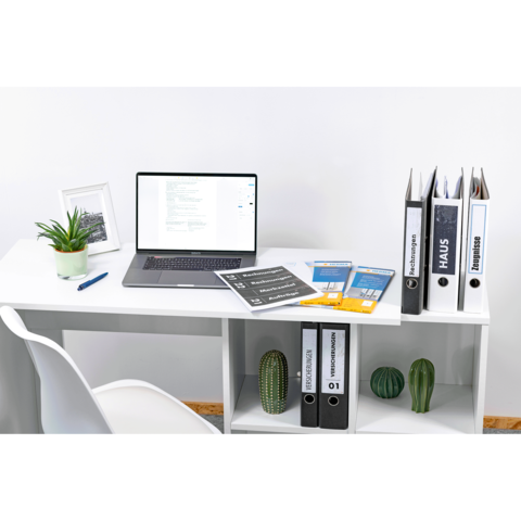 Ein Schreibtisch mit einem Laptop, mehreren Ordnern, Dokumenten und Pflanzen. Ein Stuhl steht daneben, und eine kleine Pflanze ist auf dem Tisch.