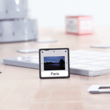 Ein Foto mit der Aufschrift "Paris" zeigt eine Landschaft mit Wasser und Bäumen, umgeben von verschiedenen Objekten auf einem Tisch.