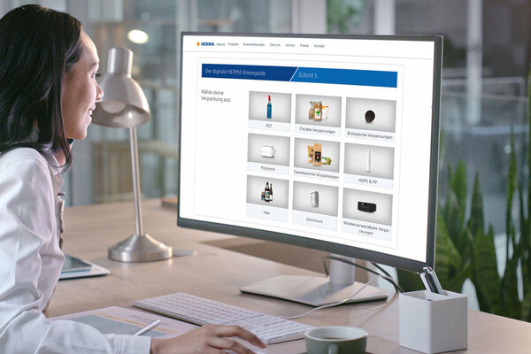Eine Person in einem weißen Laborkittel sitzt an einem Schreibtisch und betrachtet eine Computeroberfläche mit verschiedenen Produktoptionen.