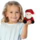 Ein Kind mit blonden Locken hält eine kleine, plüschige Weihnachtsmannfigur in der Hand und lächelt freundlich.