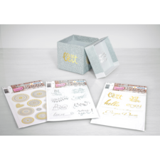 Dekorative Aufbewahrungsbox mit einem Deckel und drei Packungen mit Aufklebern, die verschiedene Designs und Schriftzüge zeigen.