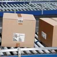 Versandetikett auf braunen Kartons, auf Förderband in der Logistik