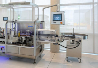 Automatisierte Verpackungsmaschine mit Förderband und Bedienfeld, verwendet für die Abfüllung und Etikettierung von Produkten.