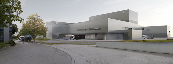 Moderne Architektur eines großen, grauen Gebäudes mit Lkw im Vordergrund und Bäumen in der Umgebung.