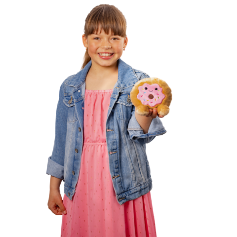 Ein Mädchen in einem rosa Kleid und einer Jeansjacke hält ein Plüschtier in Form eines Löwen mit einem Donut in der Hand.