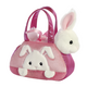 Rosa Handtasche mit einem Plüschhasen, der aus der Tasche schaut, und einem weiteren kleinen Hasen auf der Seite.