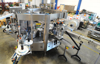 Eine komplexe Verpackungsmaschine mit mehreren Förderbändern und Etikettierstationen in einer Produktionsumgebung.