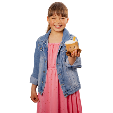 Ein Mädchen in einem rosa Kleid und einer Jeansjacke hält ein niedliches, plüschiges Getränk in der Hand und lächelt freundlich.