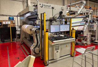Eine große Maschinenanlage zur Verarbeitung von Materialien, ausgestattet mit Steuerungstafel und Monitoren, in einer industriellen Umgebung.
