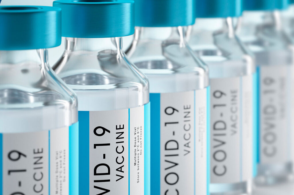 Reihe von Impfstofffläschchen mit blauen Kappen, beschriftet mit "COVID-19 Vaccine".